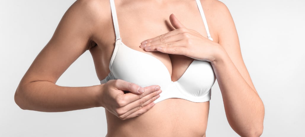 Woman examining her breasts, representing physical discomfort that leads patients to consider breast reduction surgery