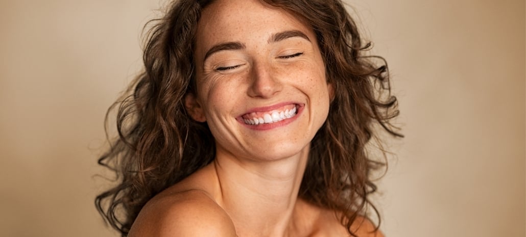 Joyful, genuinely smiling woman reflecting improved confidence and quality of life after breast augmentation