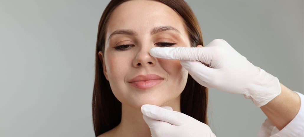 Doctor examining a patient's nose during a rhinoplasty consultation, illustrating what to expect from the procedure