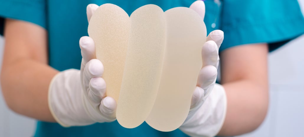 Doctor holding multiple silicone breast implants, related to breast implant illness and the option of implant removal