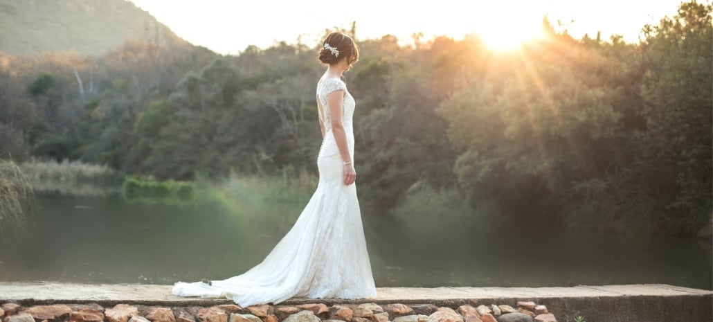 Bride in a lace wedding gown at golden hour, representing pre-wedding cosmetic preparations
