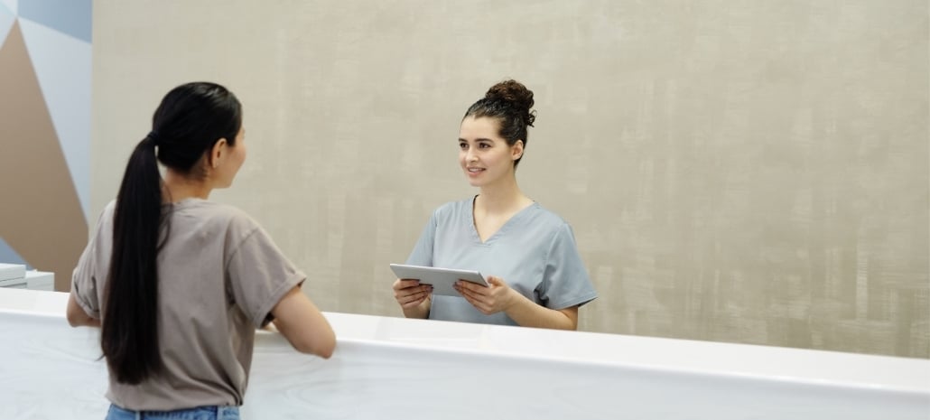 Patient reviewing paperwork with staff at a modern day surgery reception desk