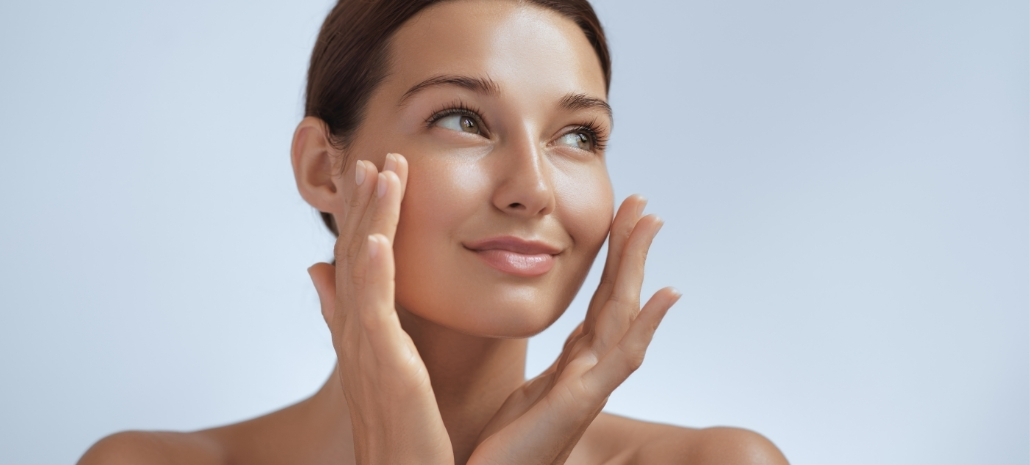 Woman with clear, glowing skin touching her face, representing tips for a clear complexion