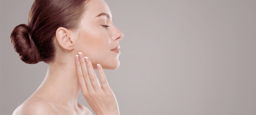 Profile of a woman touching her jawline, highlighting smooth facial and neck contours