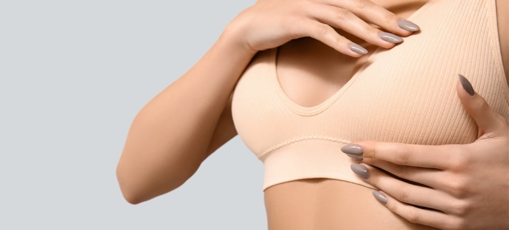 Woman gently touching her chest, representing a natural-looking breast augmentation result