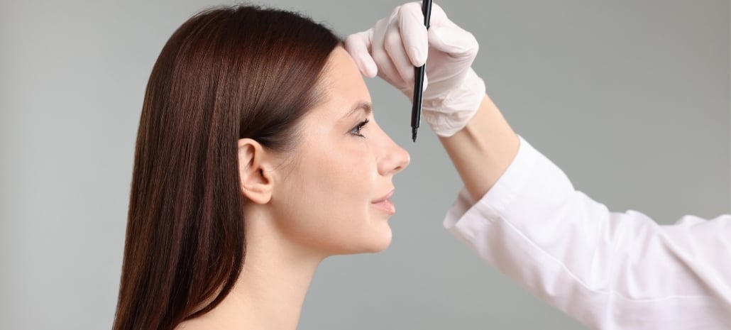 Surgeon marking a patient's nose in profile before rhinoplasty, illustrating surgical planning